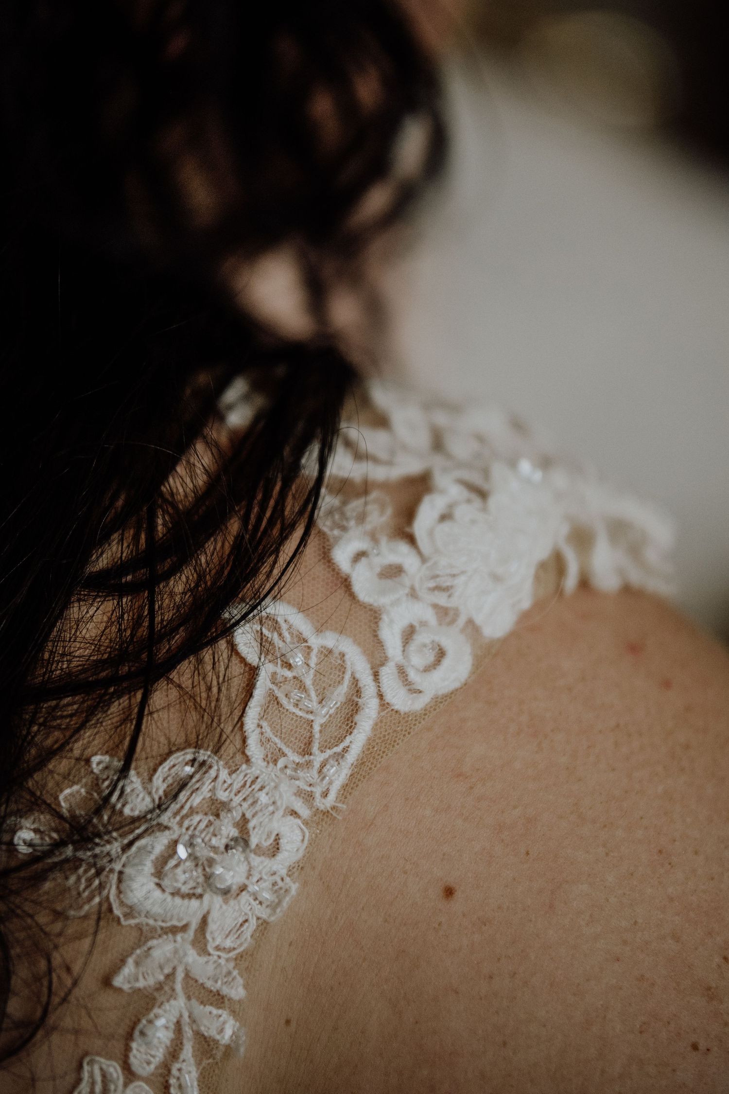 Close-up detail of delicate white lace pattern on a wedding dress.