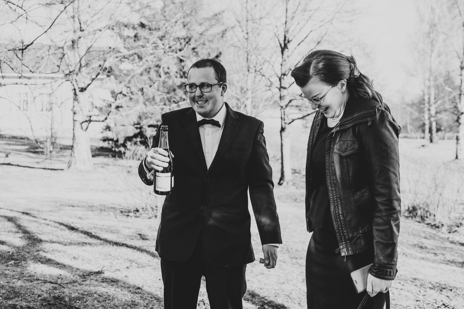 Black and white photo of two people in formal attire walking outdoors in winter.