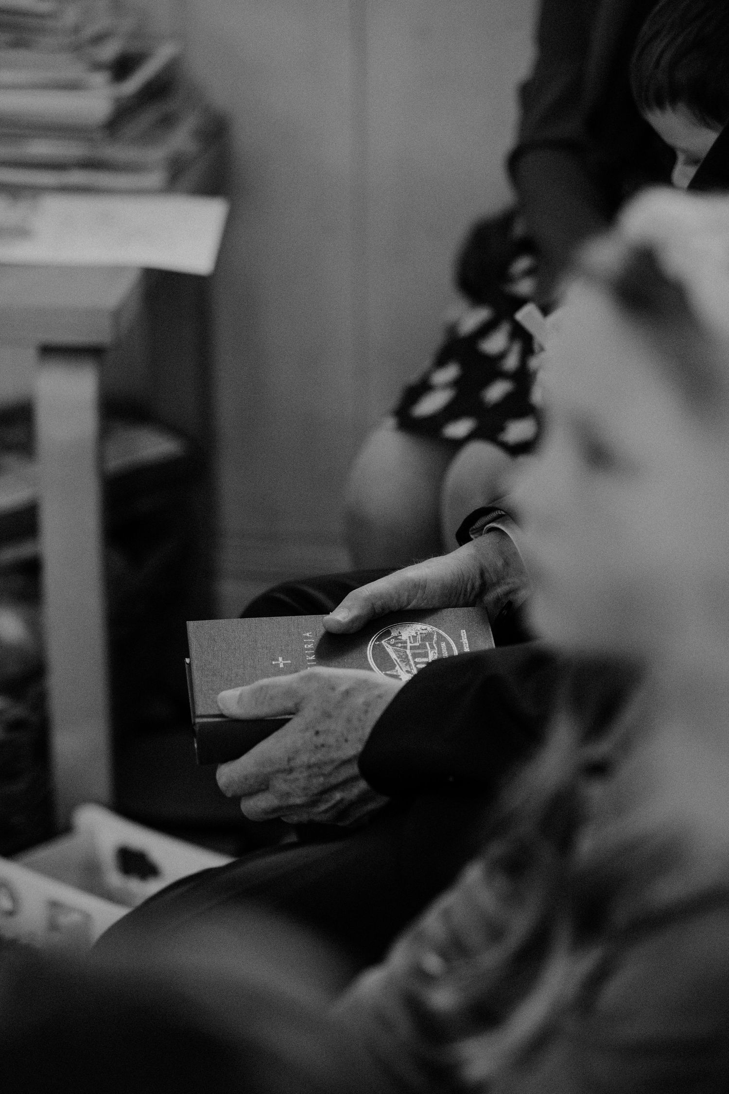 Black and white image of hands holding a small book or document.