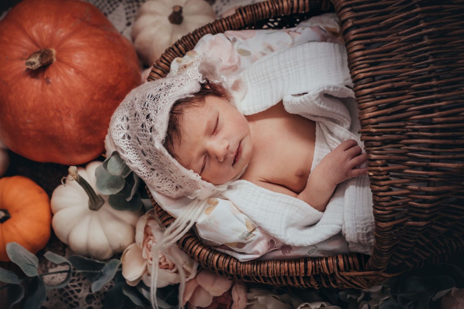 top down view of sleeping baby in a bonnet surrounded by pumpkins