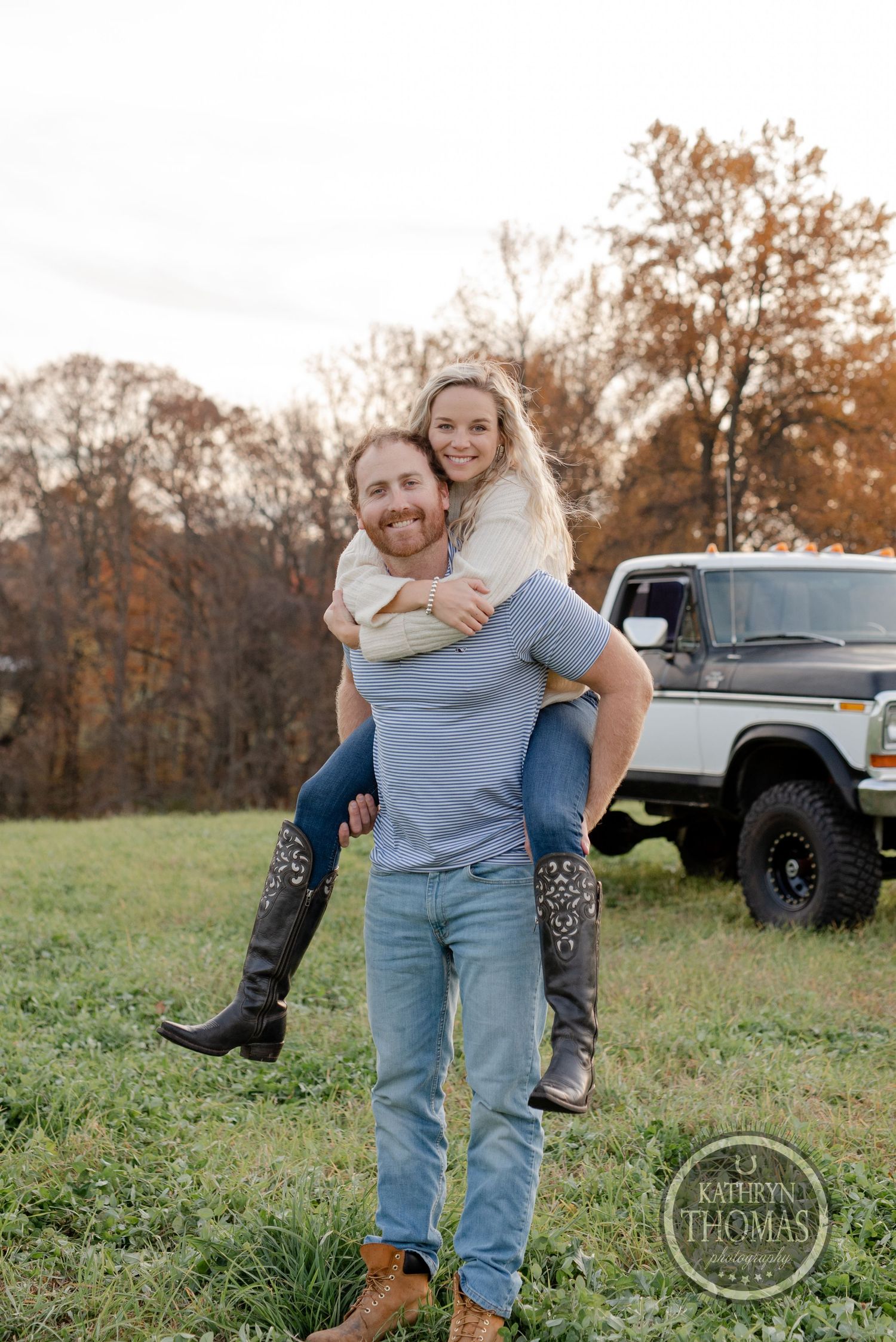 Playful piggyback ride in front of a lifted vintage truck during an autumn countryside photoshoot.