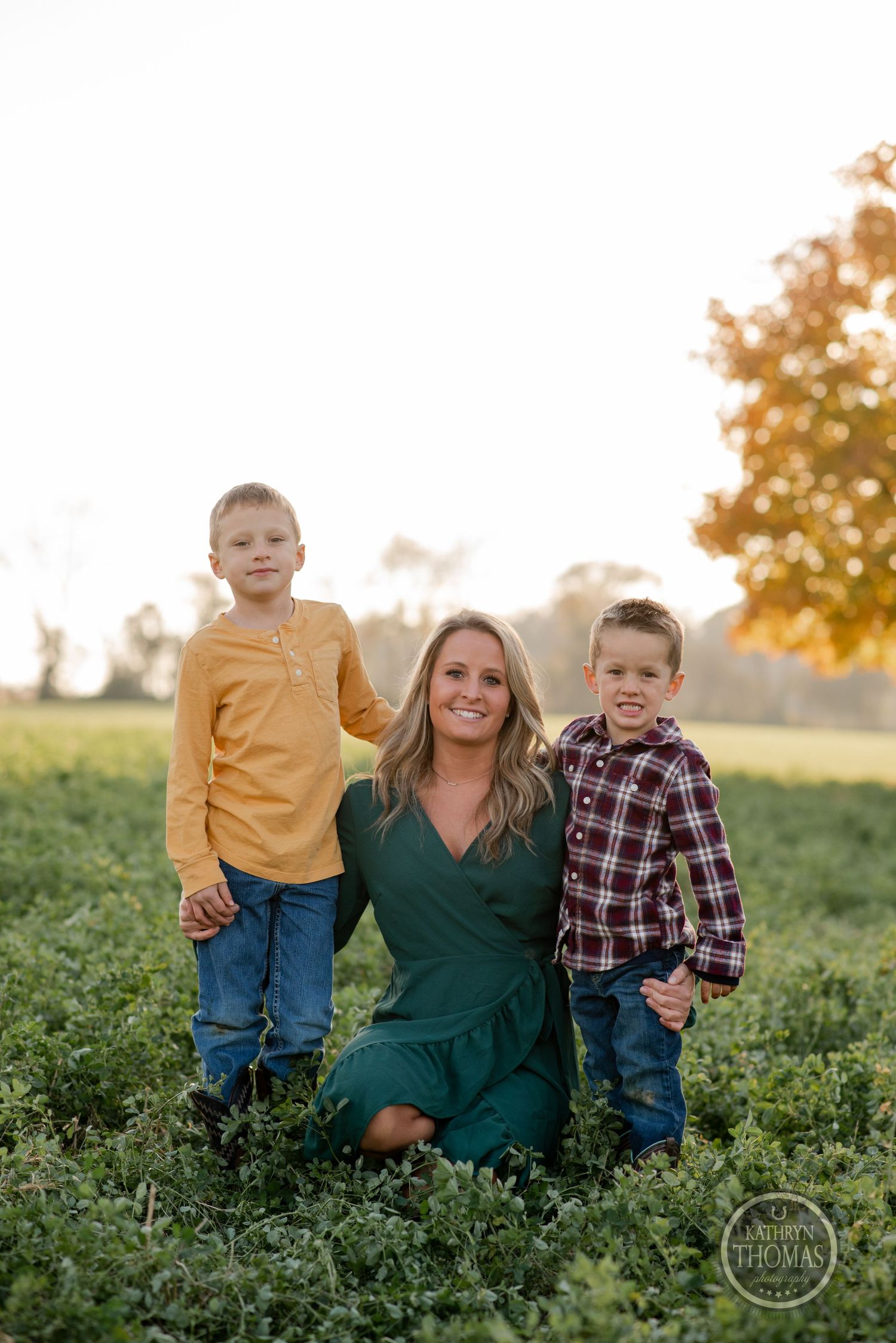 Family portrait in green field during sunset with golden autumn colors.