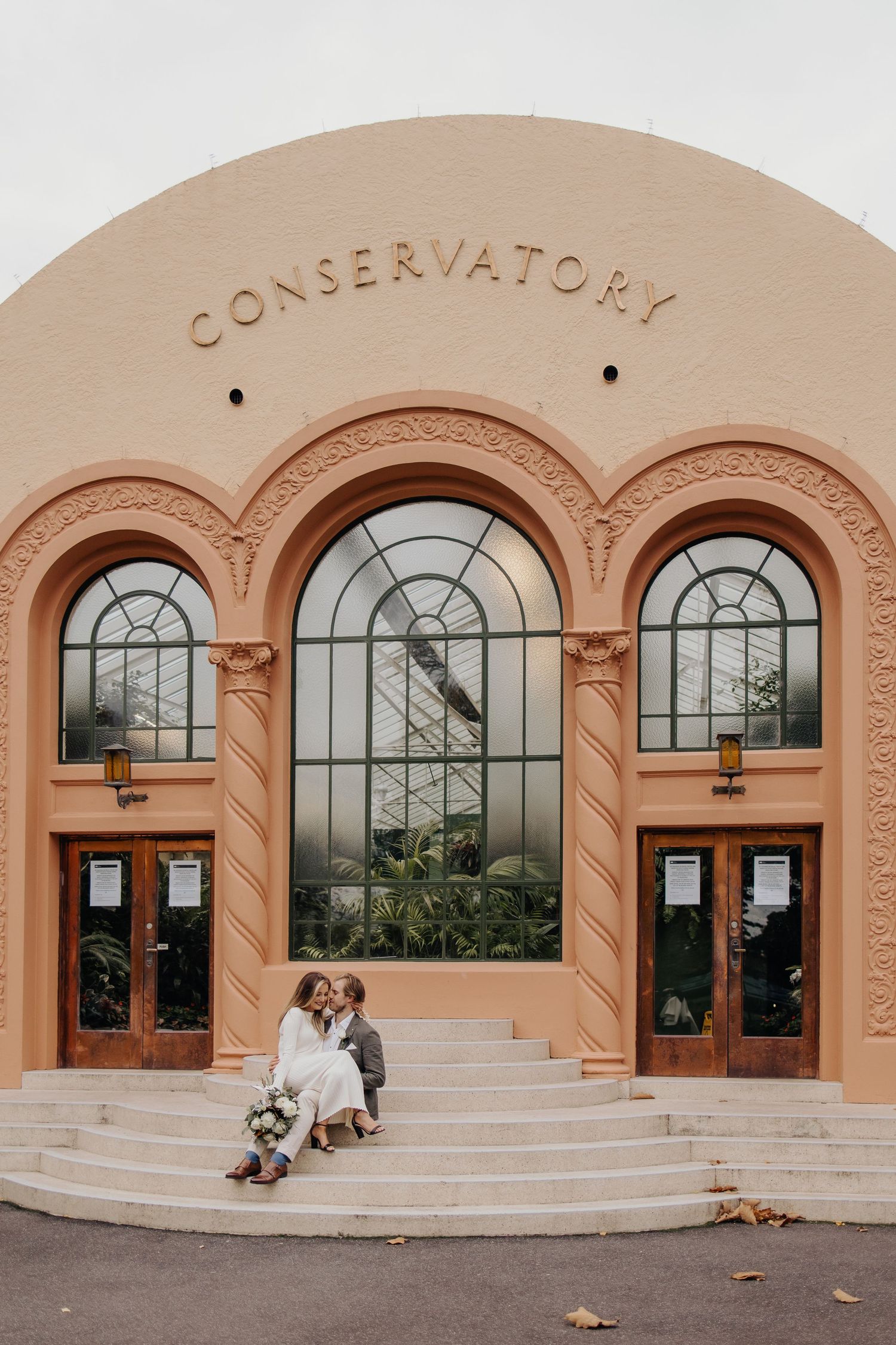 Exterior view of conservatory building with peach walls and arched windows.