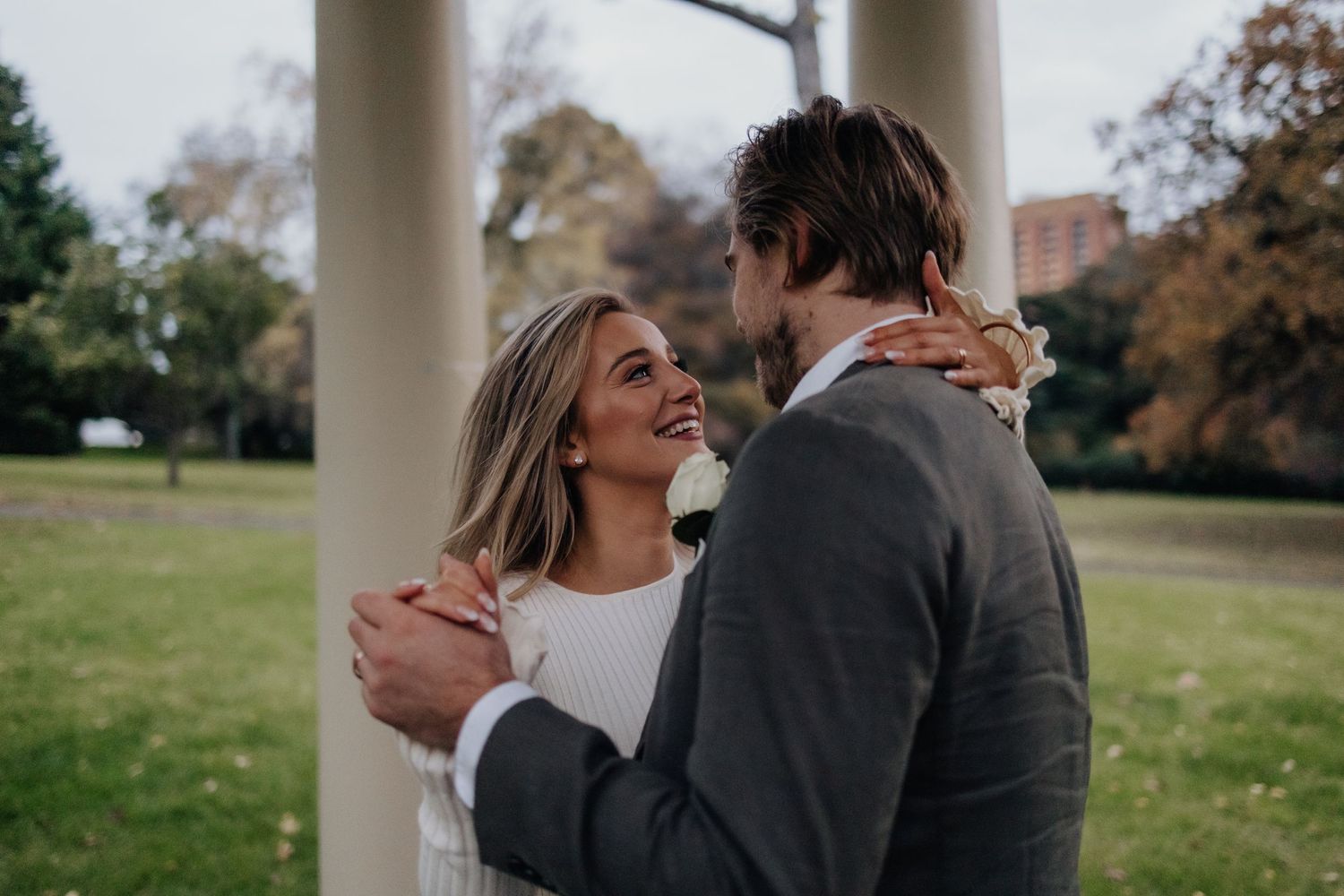 Wedding couple sharing intimate moments between white classical columns.