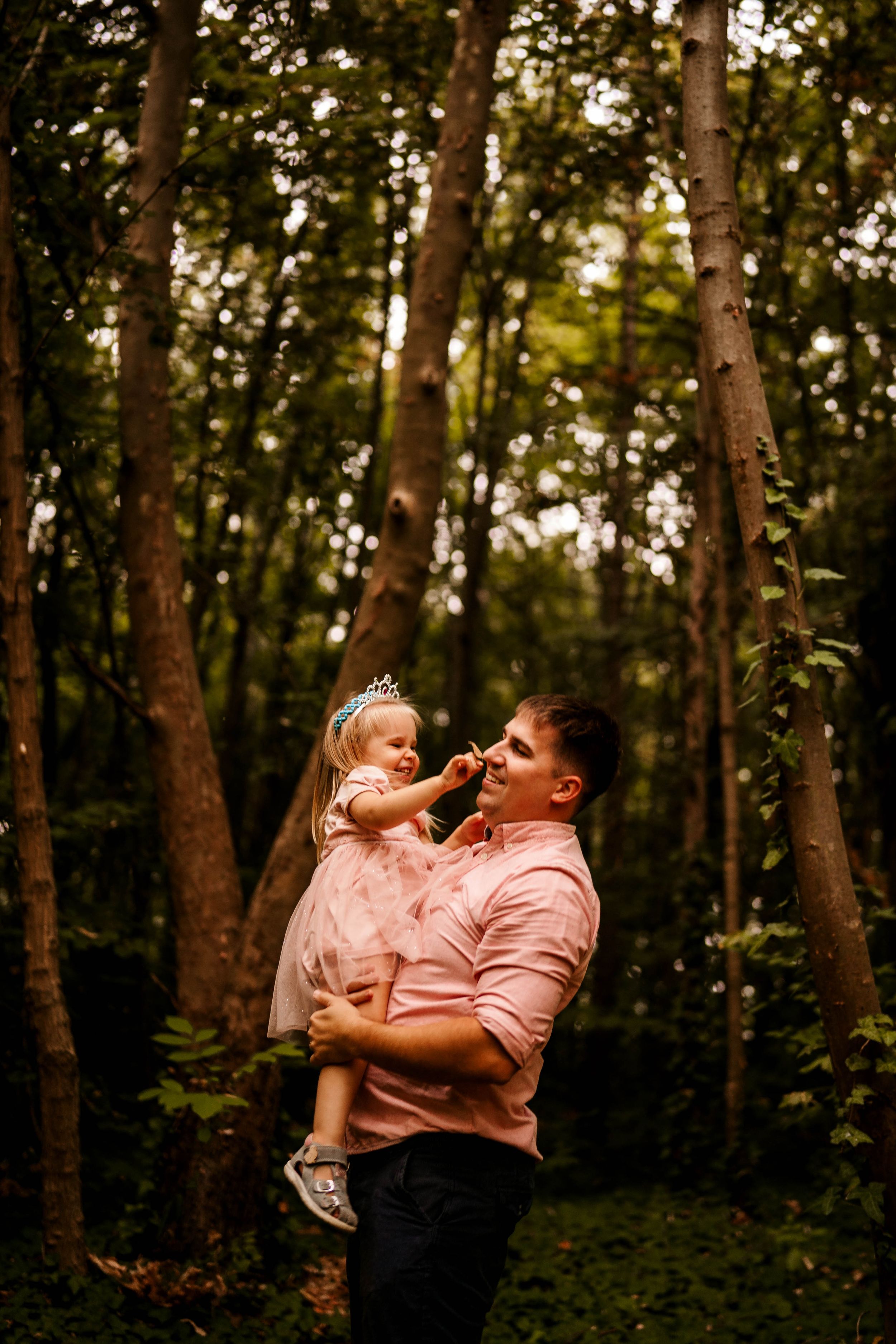 A tender moment captured in a wooded forest setting with warm lighting and natural surroundings.