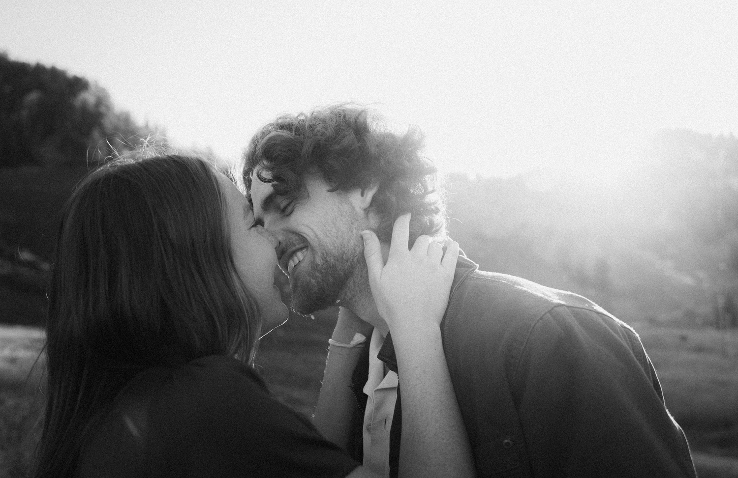 An intimate black and white portrait of a couple sharing a tender moment in natural light.