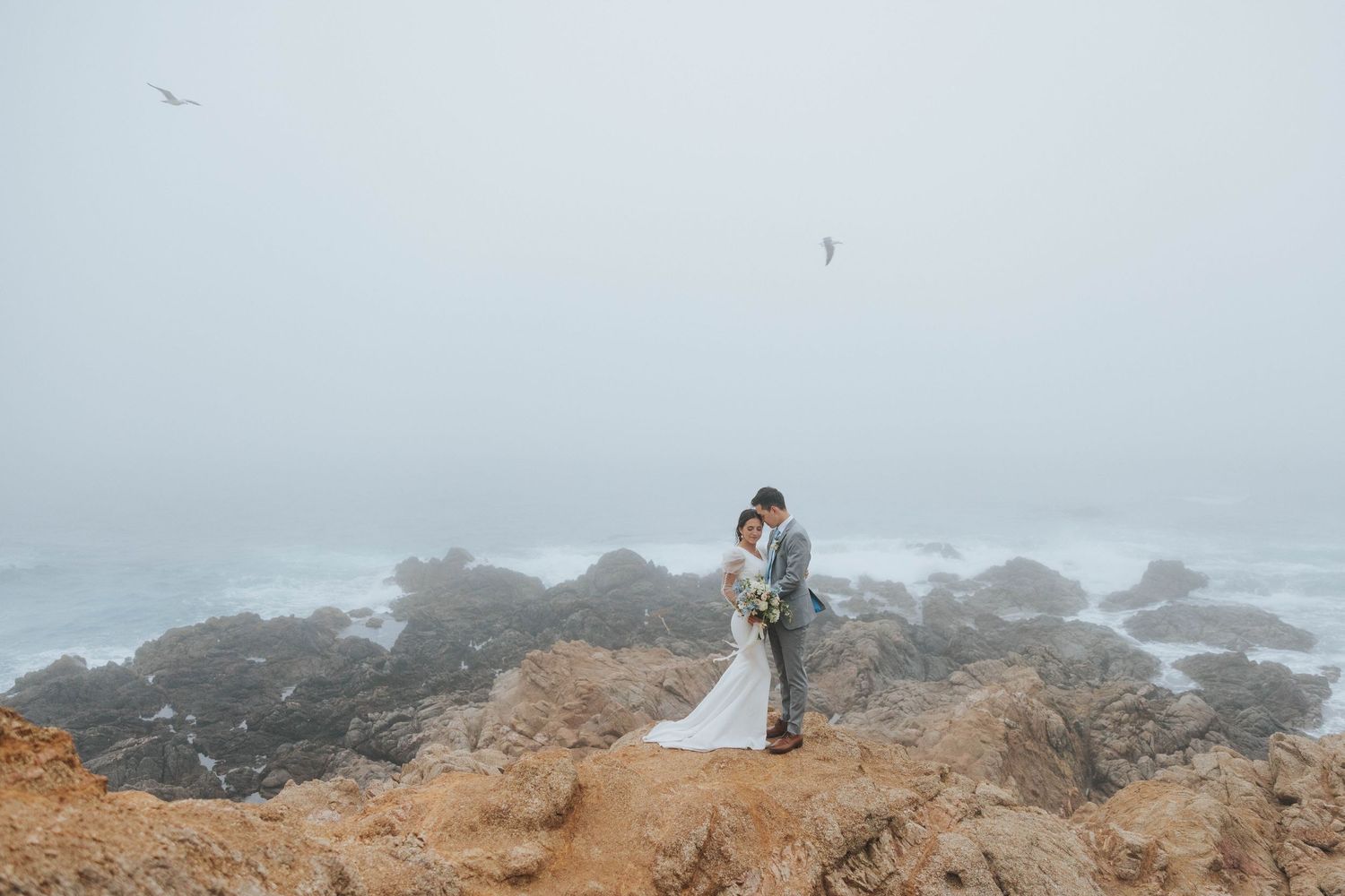 A couple stands near a stunning overlook in Big Sur, CA as they pose for their destination wedding photographer.