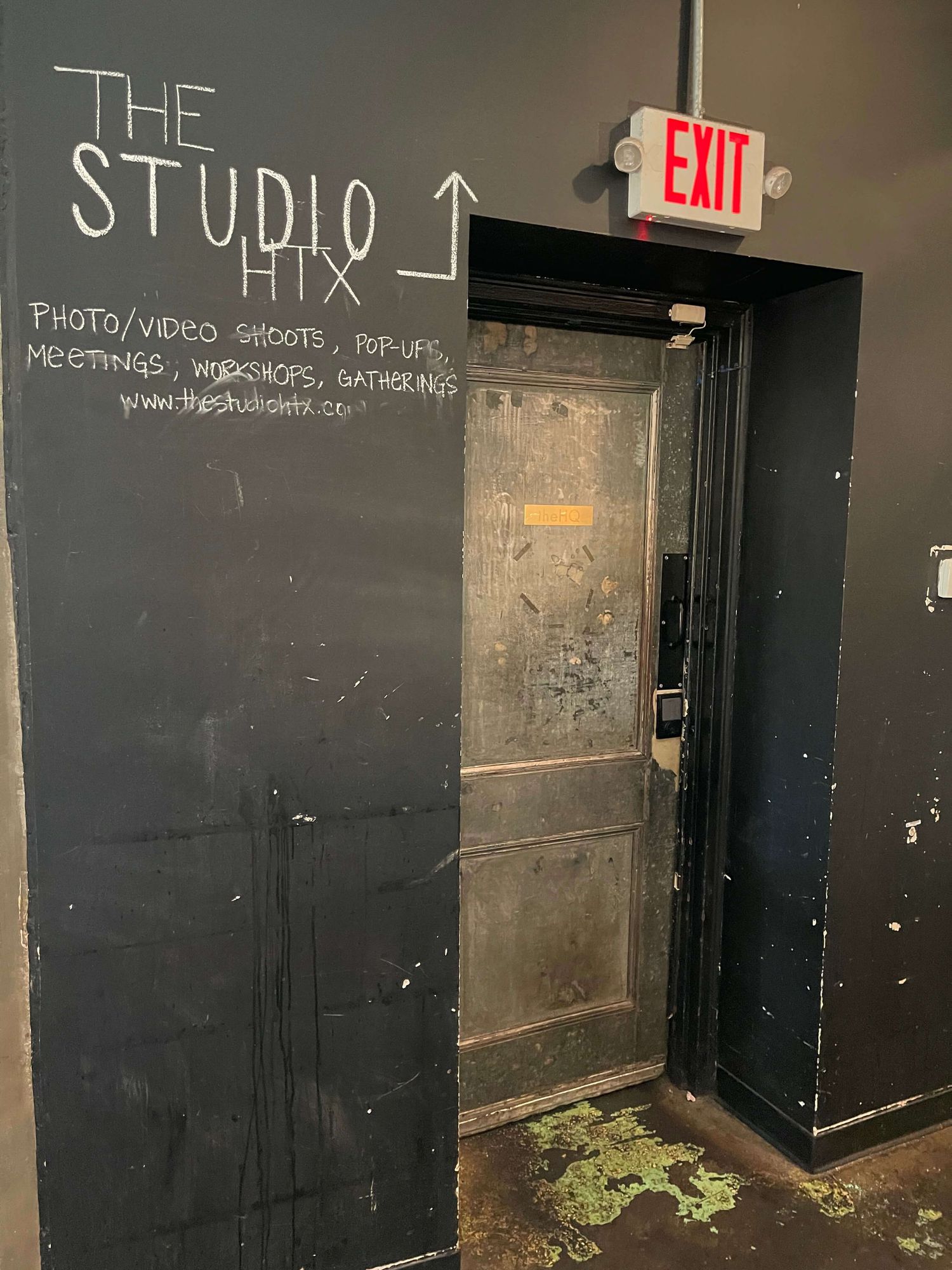 Dark hallway with black walls showing exit signs and directional text.
