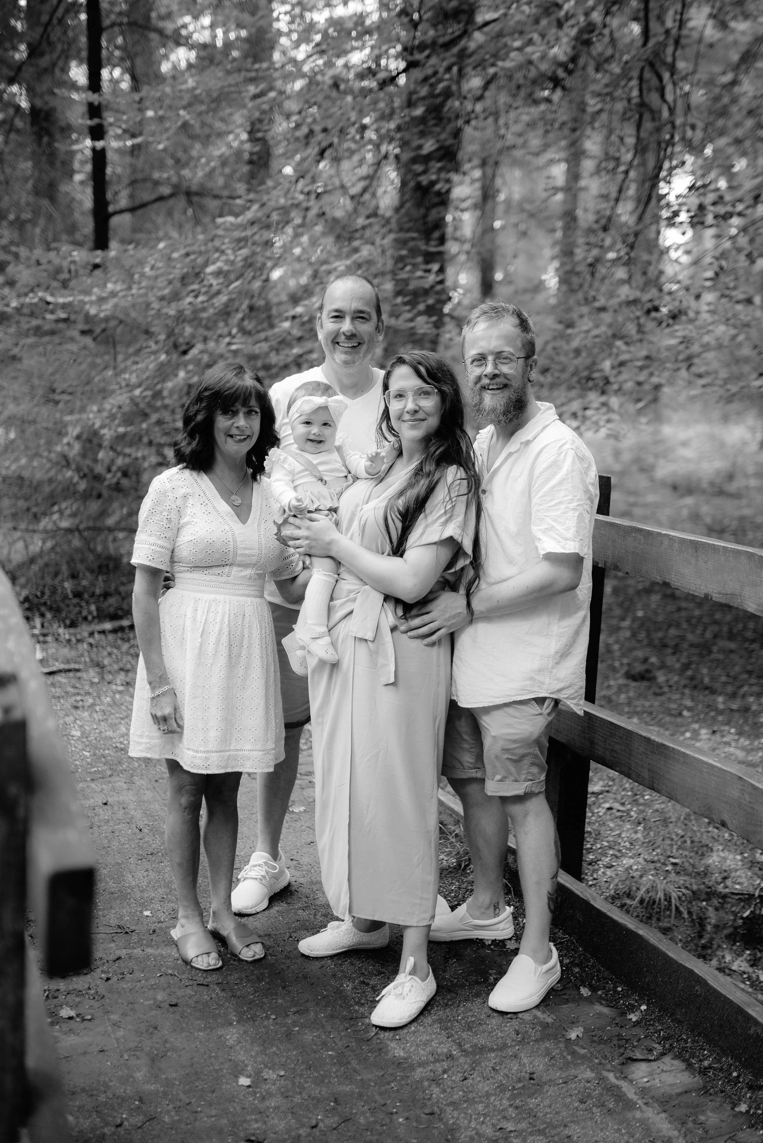 A group stands together outdoors on a wooded path, all wearing light colored clothing in this black and white photo.