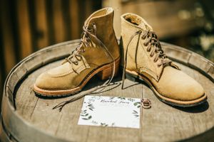 Vintage brown leather boots displayed on wooden barrel with note card.