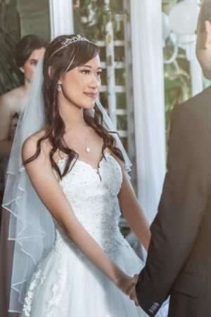 Elegant bride in white lace dress and tiara during wedding ceremony.