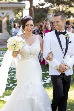 A joyful wedding ceremony moment in a garden setting with white flowers and elegant attire.