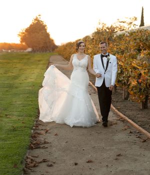 A couple walking along a path at sunset with the bride's dress flowing in the breeze.