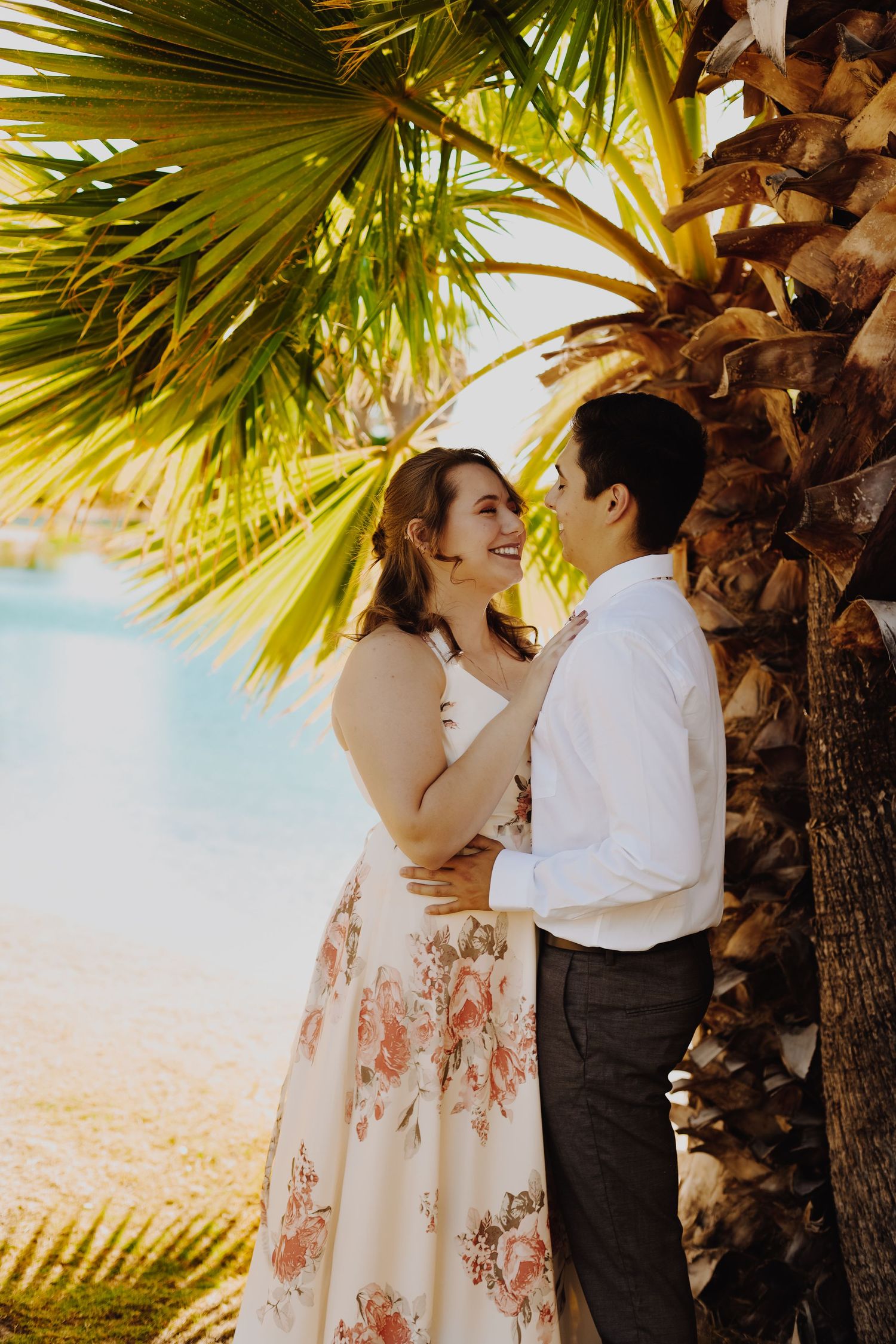 Romantic portrait under palm trees during golden hour with dreamy desert backdrop.