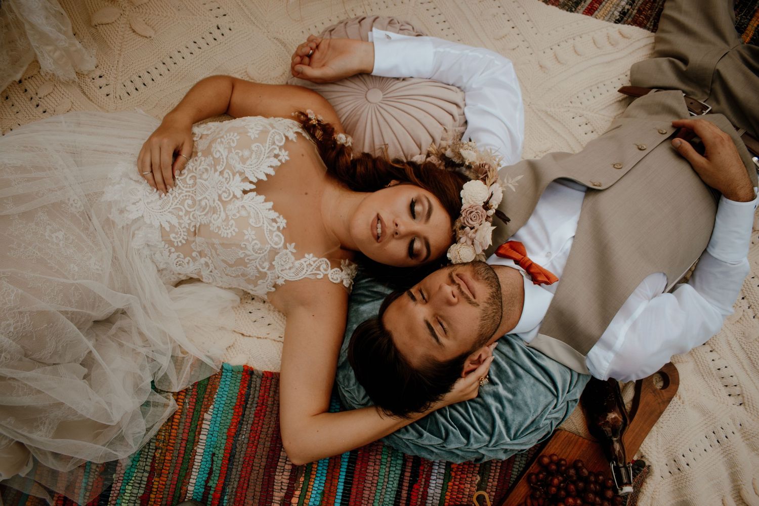 A couple lying together on a blanket with the person in a white lace dress.