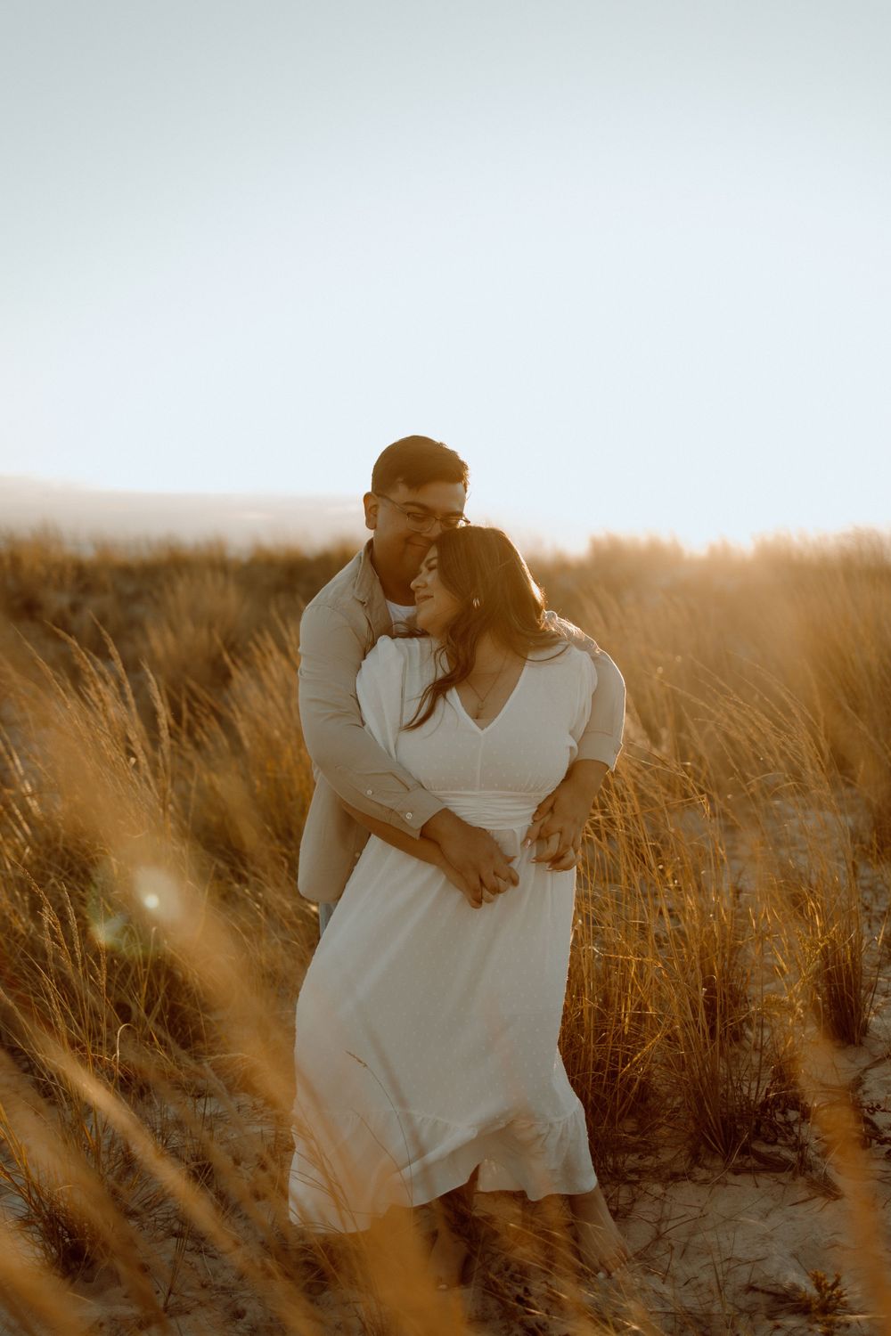 A tender embrace captured in warm sunlight among tall golden grasses.
