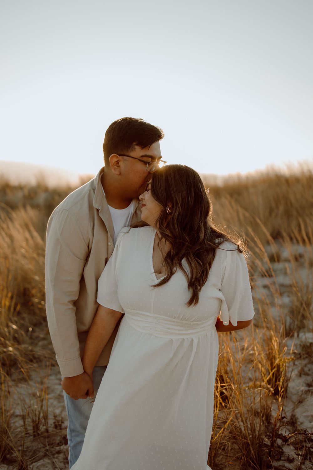 An intimate moment captured in warm sunset light among coastal dune grasses.