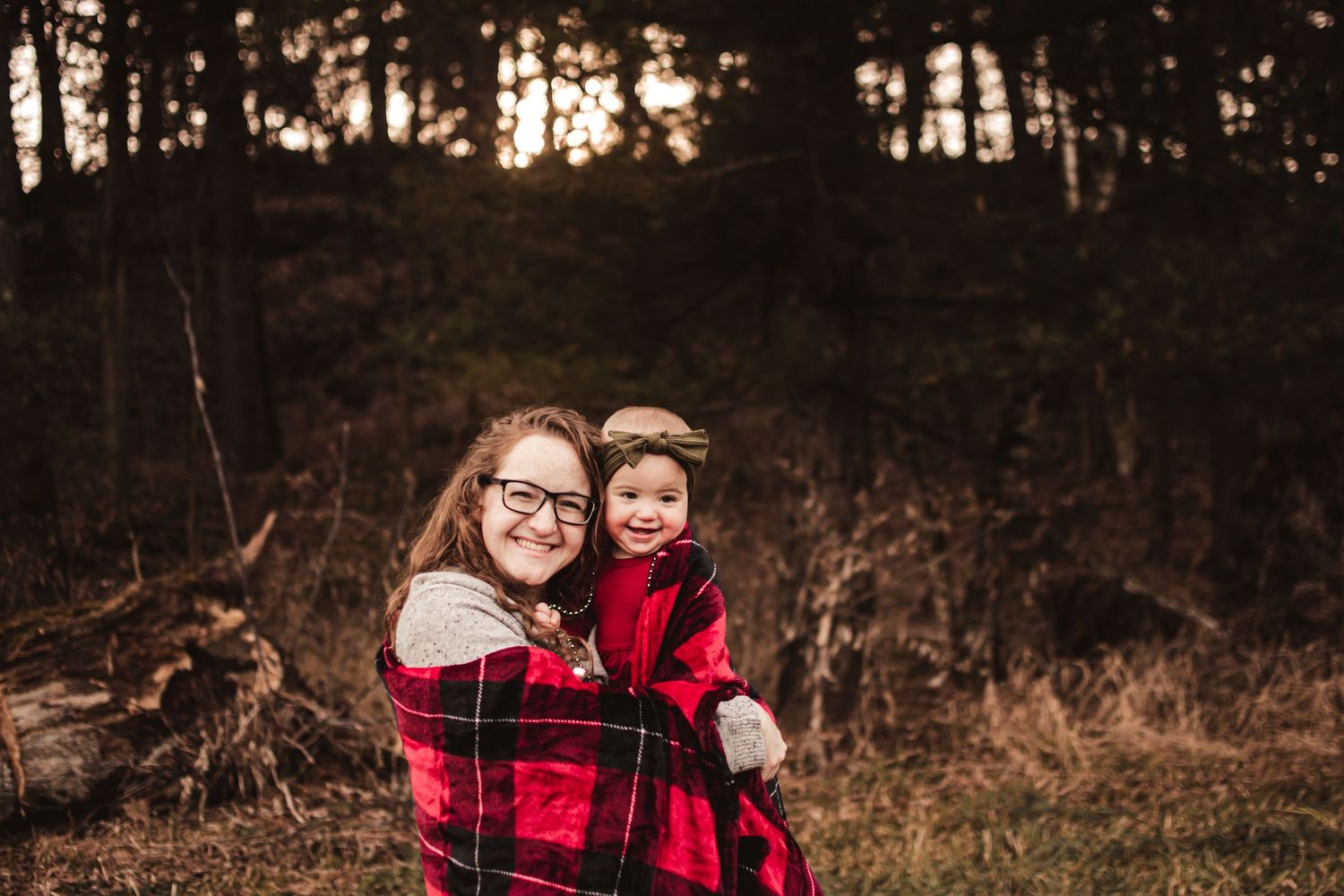Cozy autumn outdoor portrait with red plaid and warm smiles in the woods.
