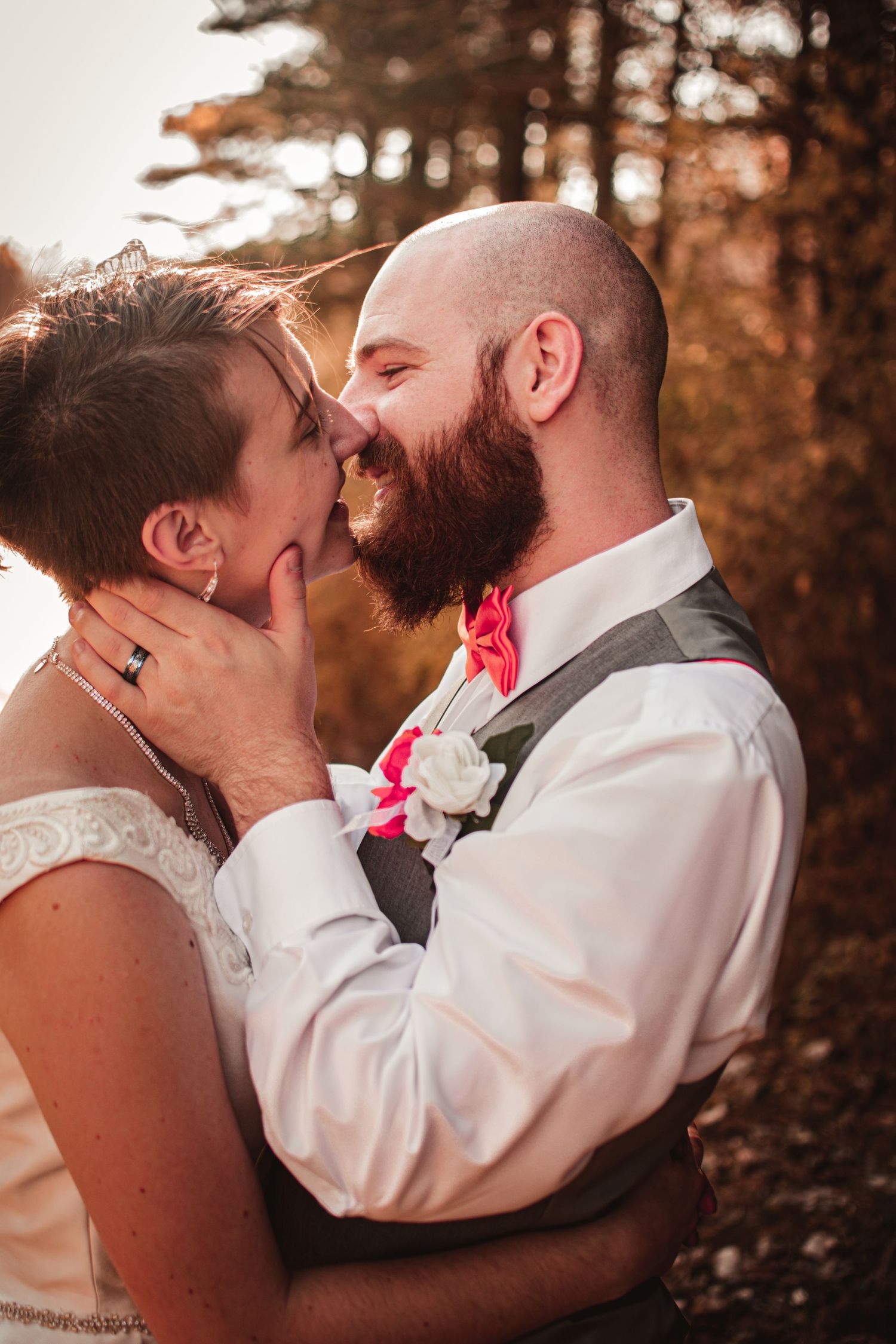 Intimate wedding portrait of couple sharing tender moment in forest setting.