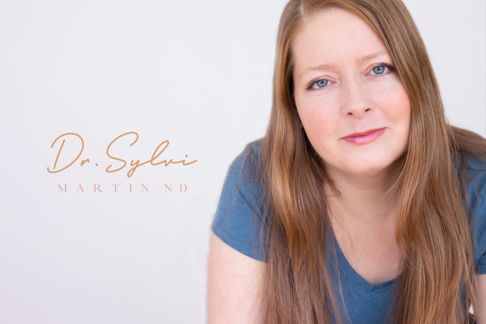 Professional headshot portrait against white background with soft blue top and natural lighting.