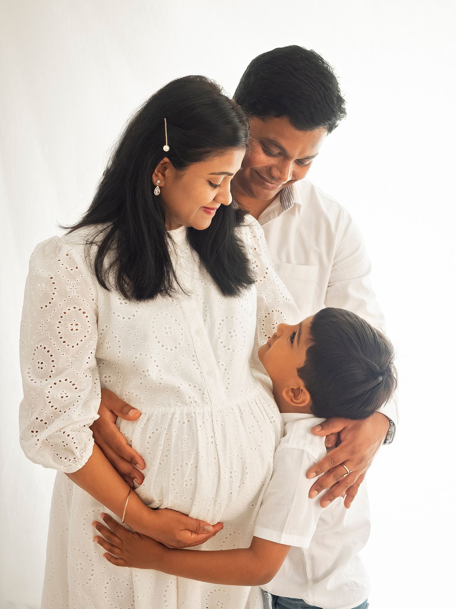 Family wearing white pose looking at each other during maternity photoshoot in Didcot with Verity Photography