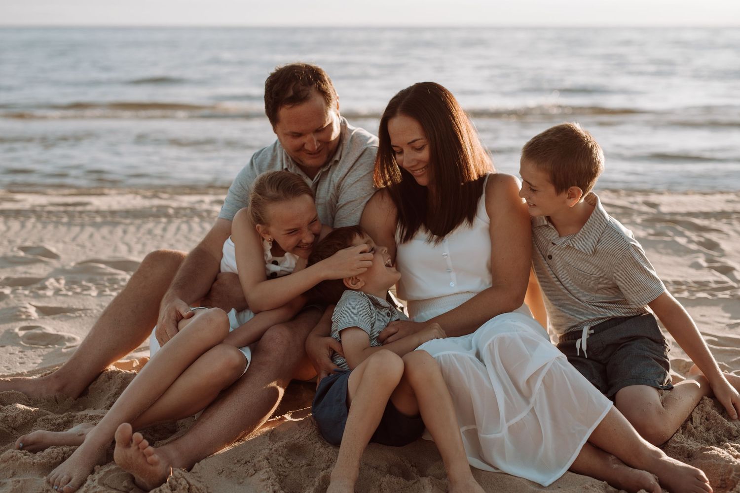A joyful beach scene at sunset with warm golden light.