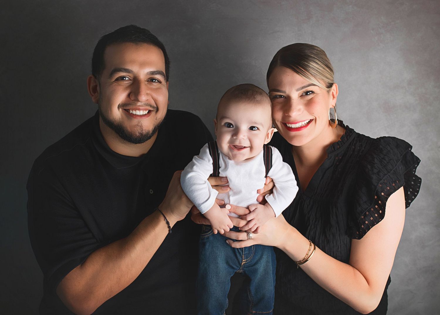 Studio family portrait with modern styling against dark gray backdrop.