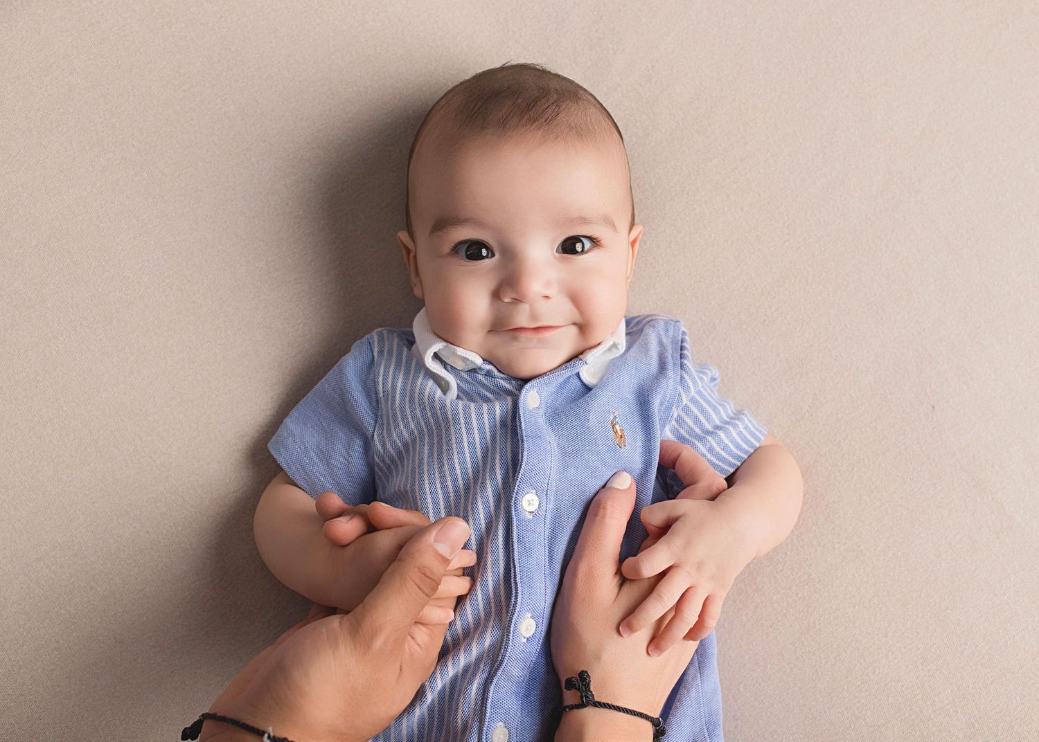 Baby in light blue button-down shirt smiles during portrait session.