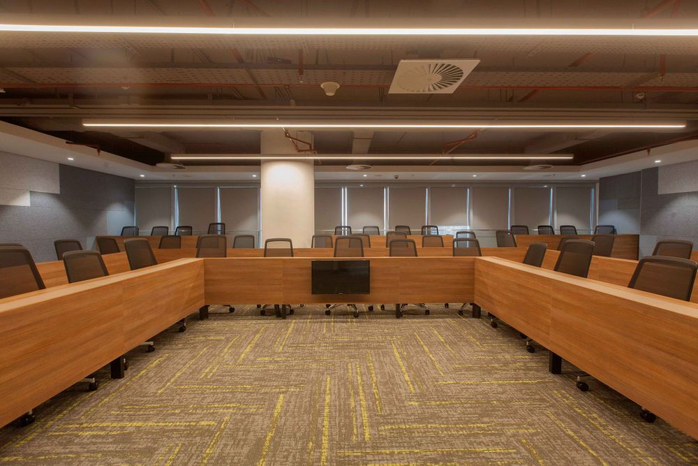 Modern conference room with wooden paneling and tiered seating arranged in a curved amphitheater style layout.