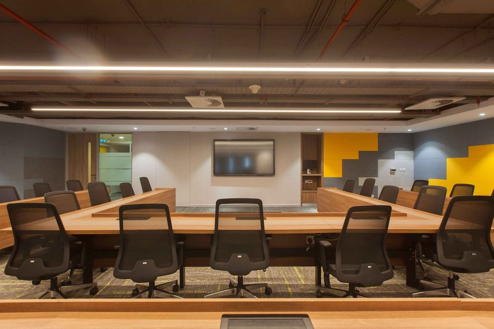 Contemporary office space with rows of ergonomic chairs and sleek lighting fixtures mounted on the ceiling.