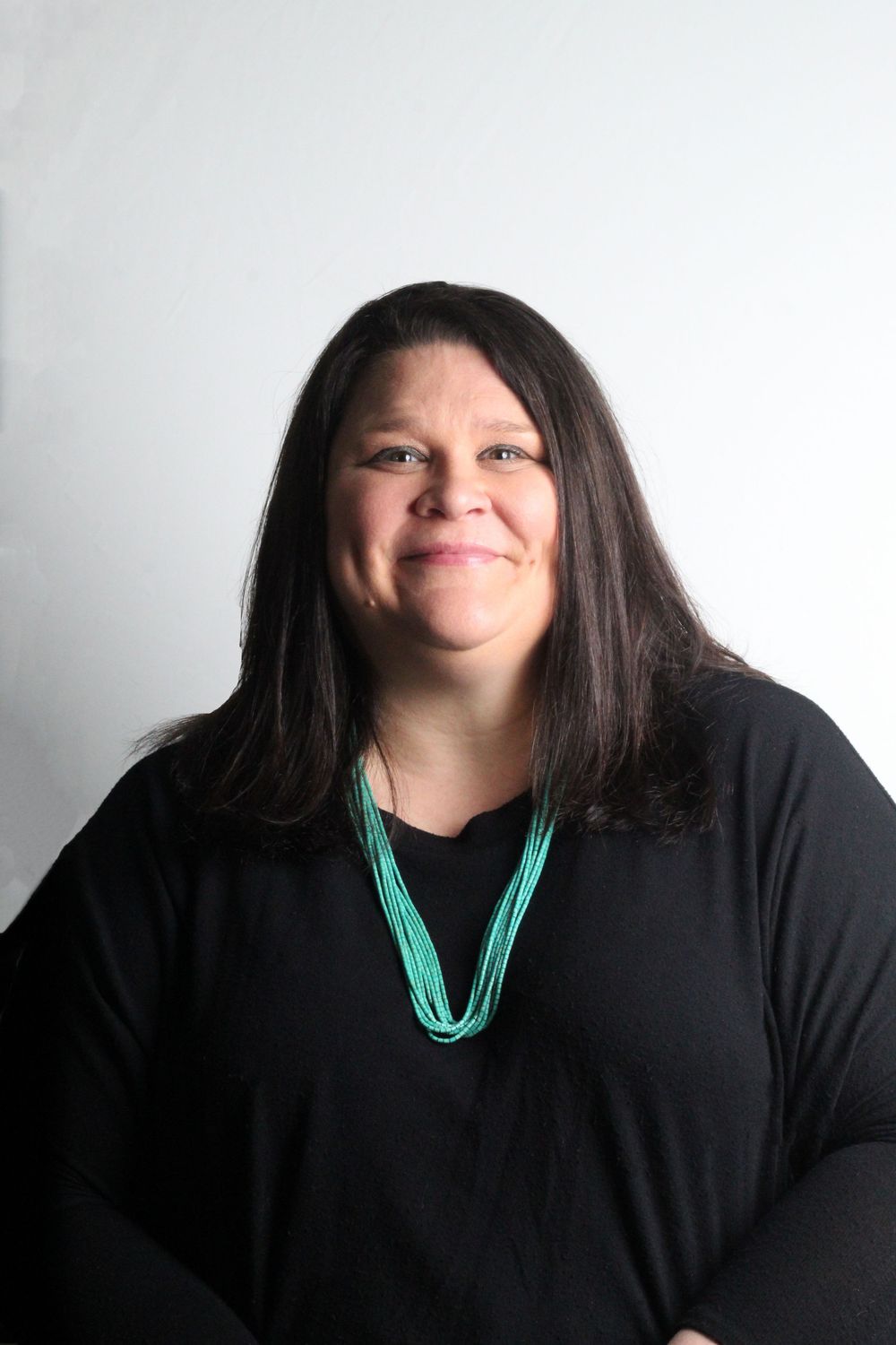 Studio portrait against white background featuring turquoise beaded necklace.