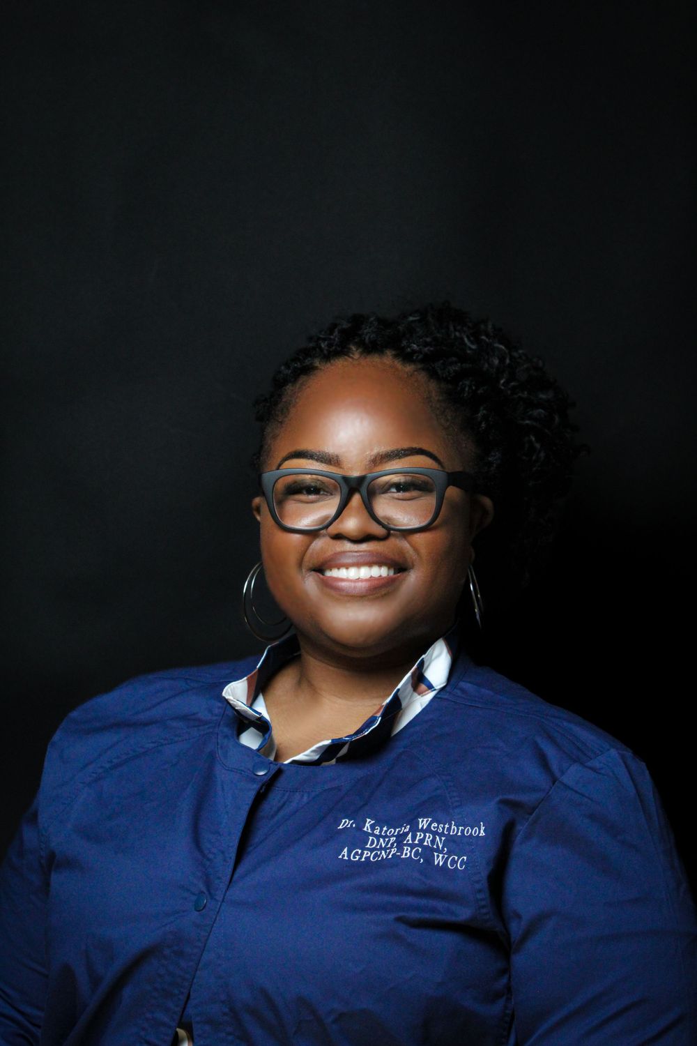 Professional portrait in navy blue uniform against dark background.
