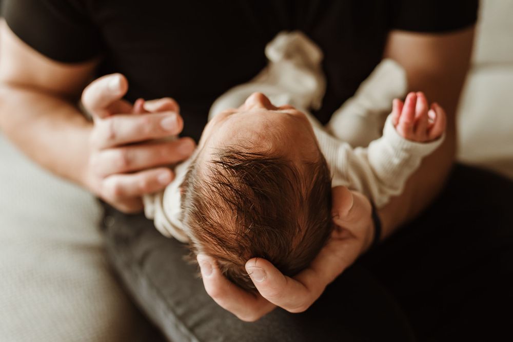 newborn baby cradled in fathers hands