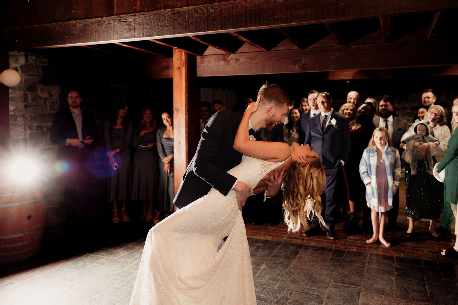 Wedding reception dance party in dimly lit rustic barn venue.