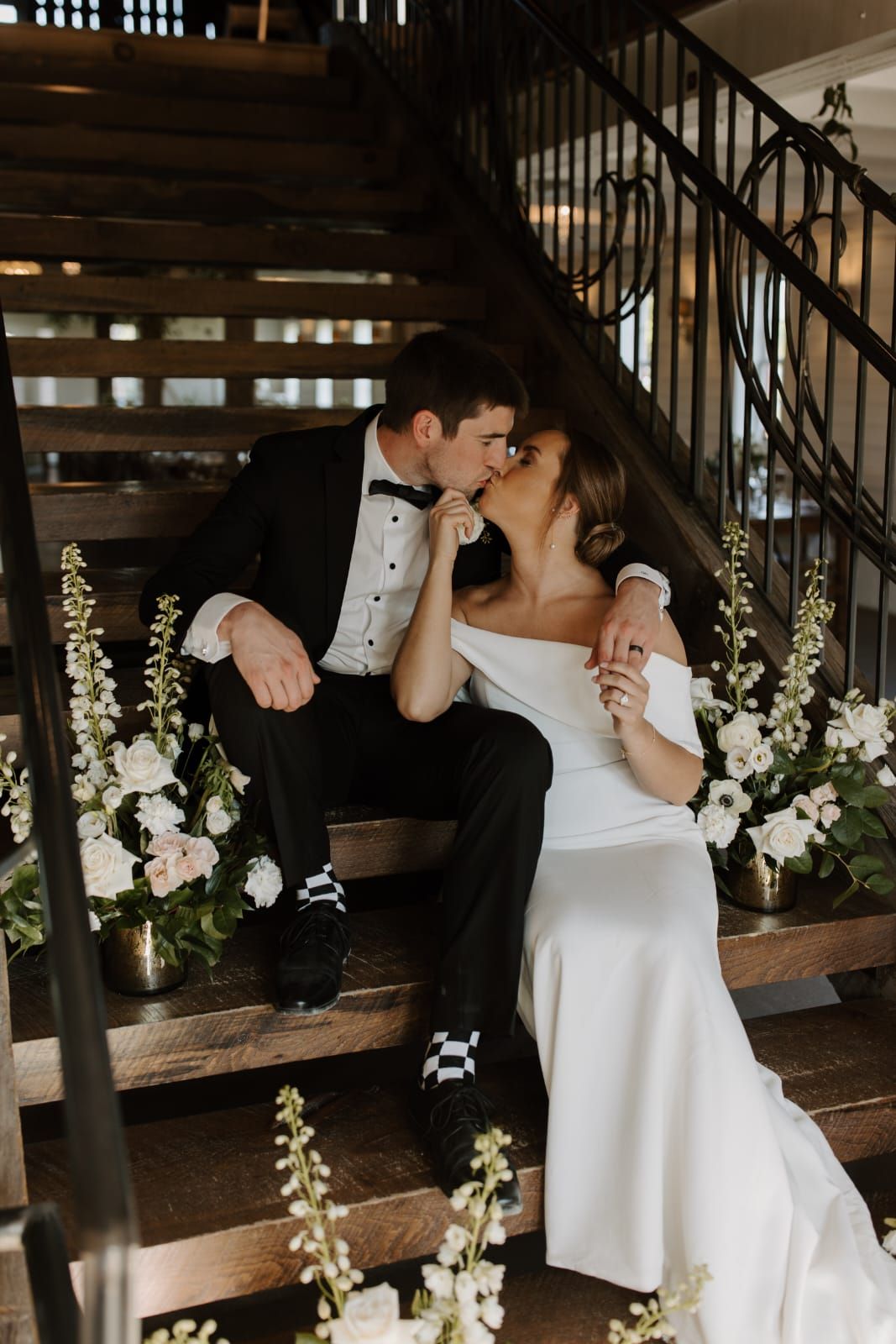 Romantic wedding moment captured in rustic barn setting with white floral arrangements.