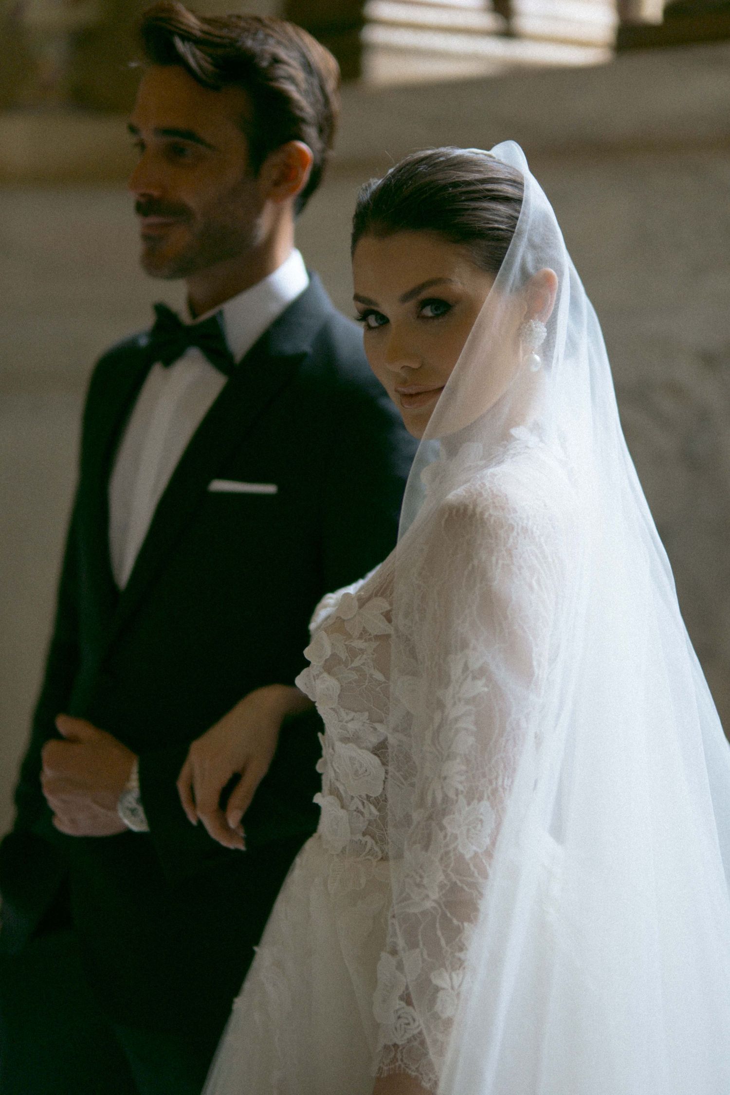 Classic wedding portrait series showing elegant white lace gown and formal attire in dim lighting.