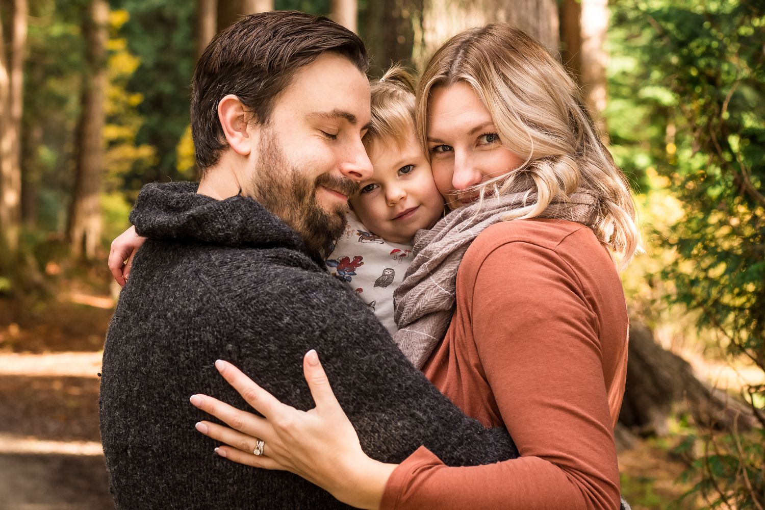 Family snuggled in a tight embrace in a beautiful forest.