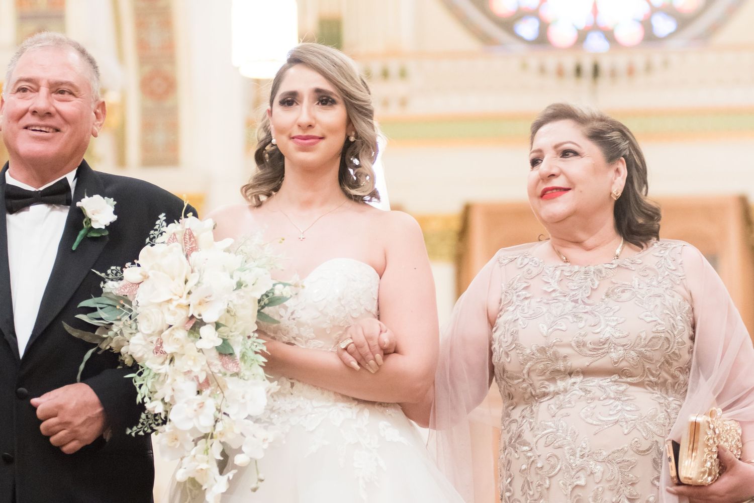 closeup of bride accompanied by her parents at a traditional church wedding ceremony.