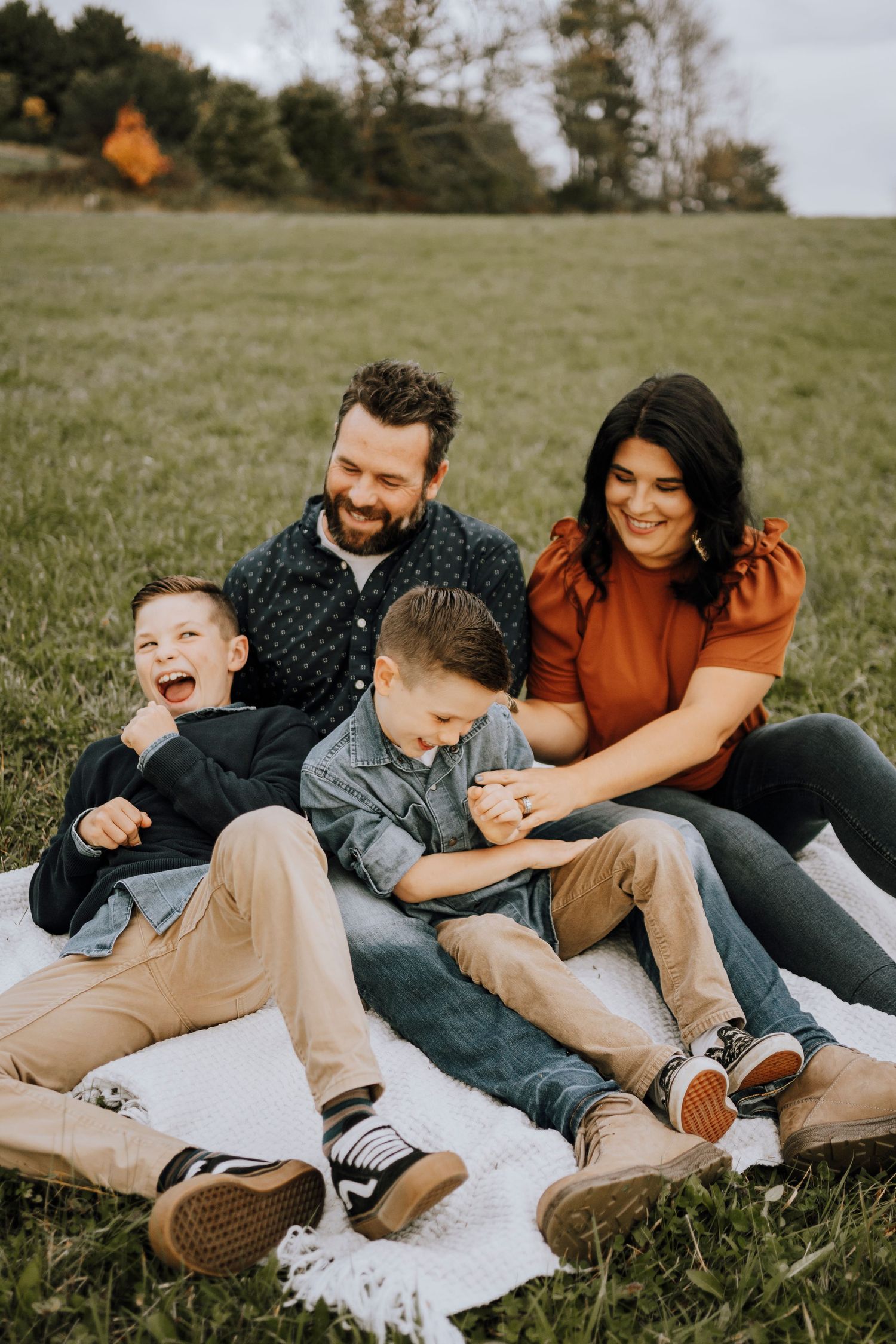 Family enjoying quality time together while relaxing on blanket in grassy field.