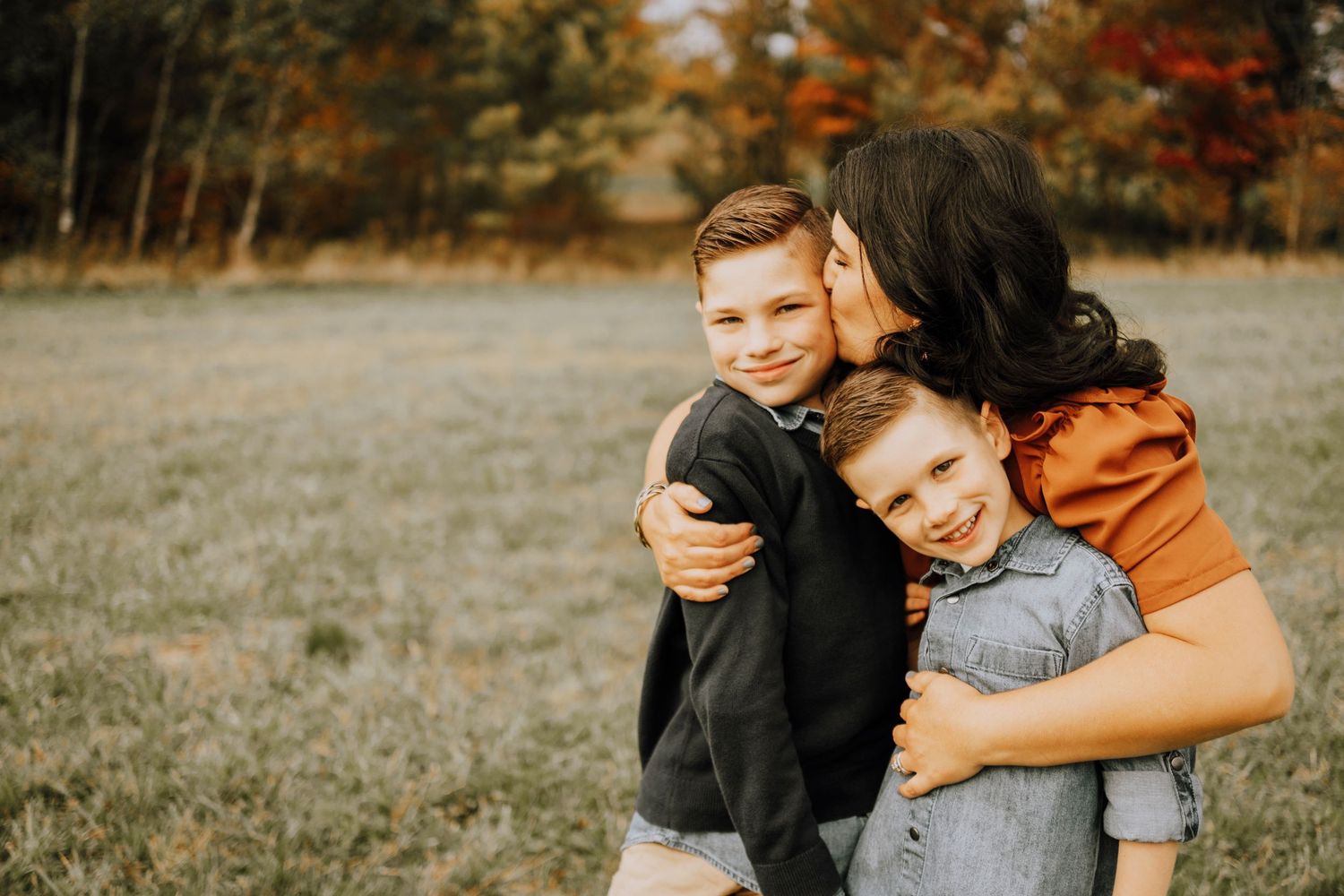 Candid moment of family members hugging and sharing joyful expressions outdoors.