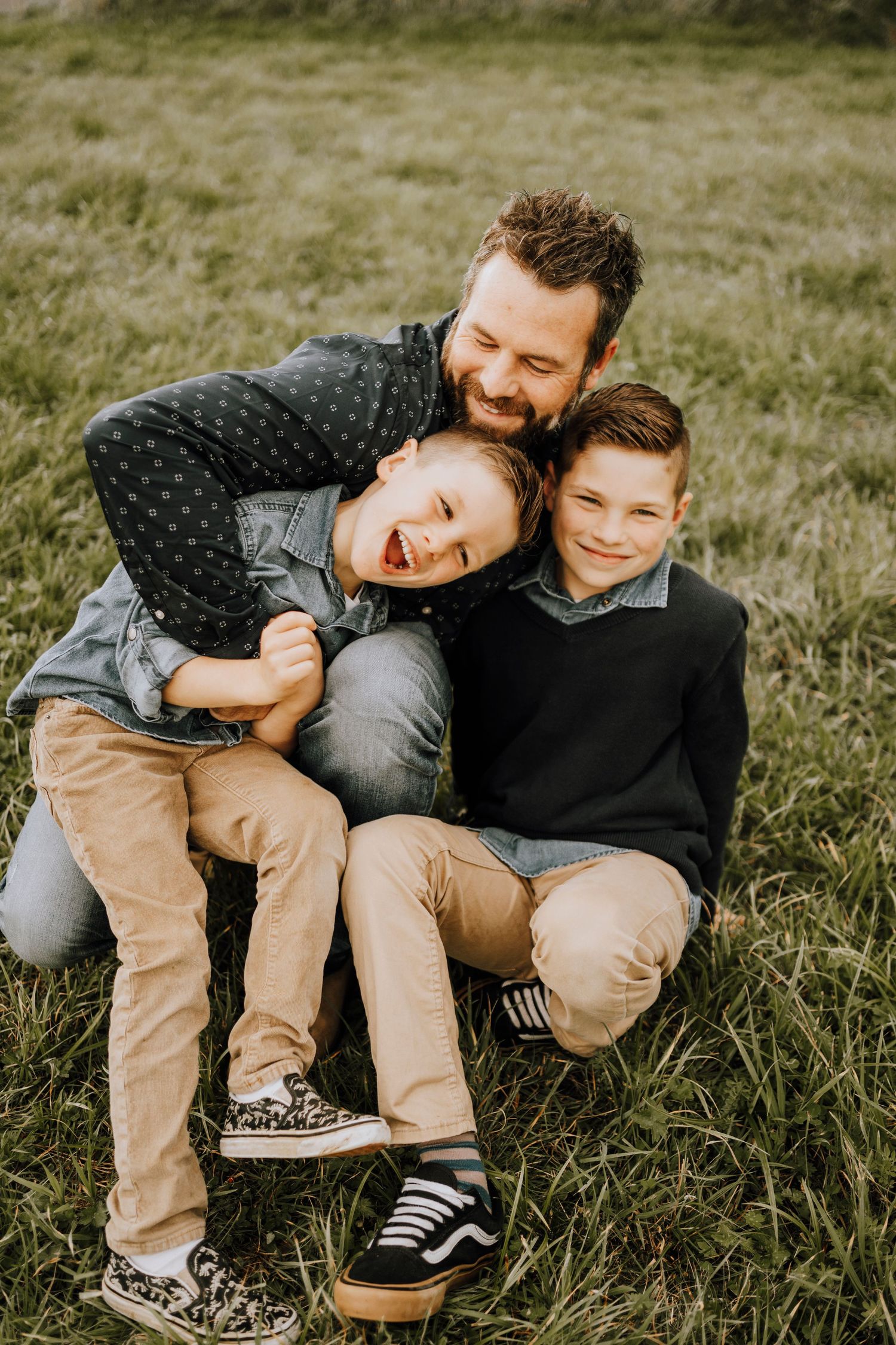 Playful family moment captured on grass with everyone laughing and embracing.