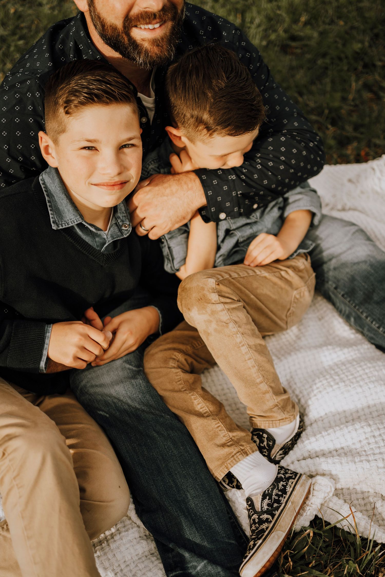 Candid family moment showing laughter and connection while sitting on blanket outdoors.