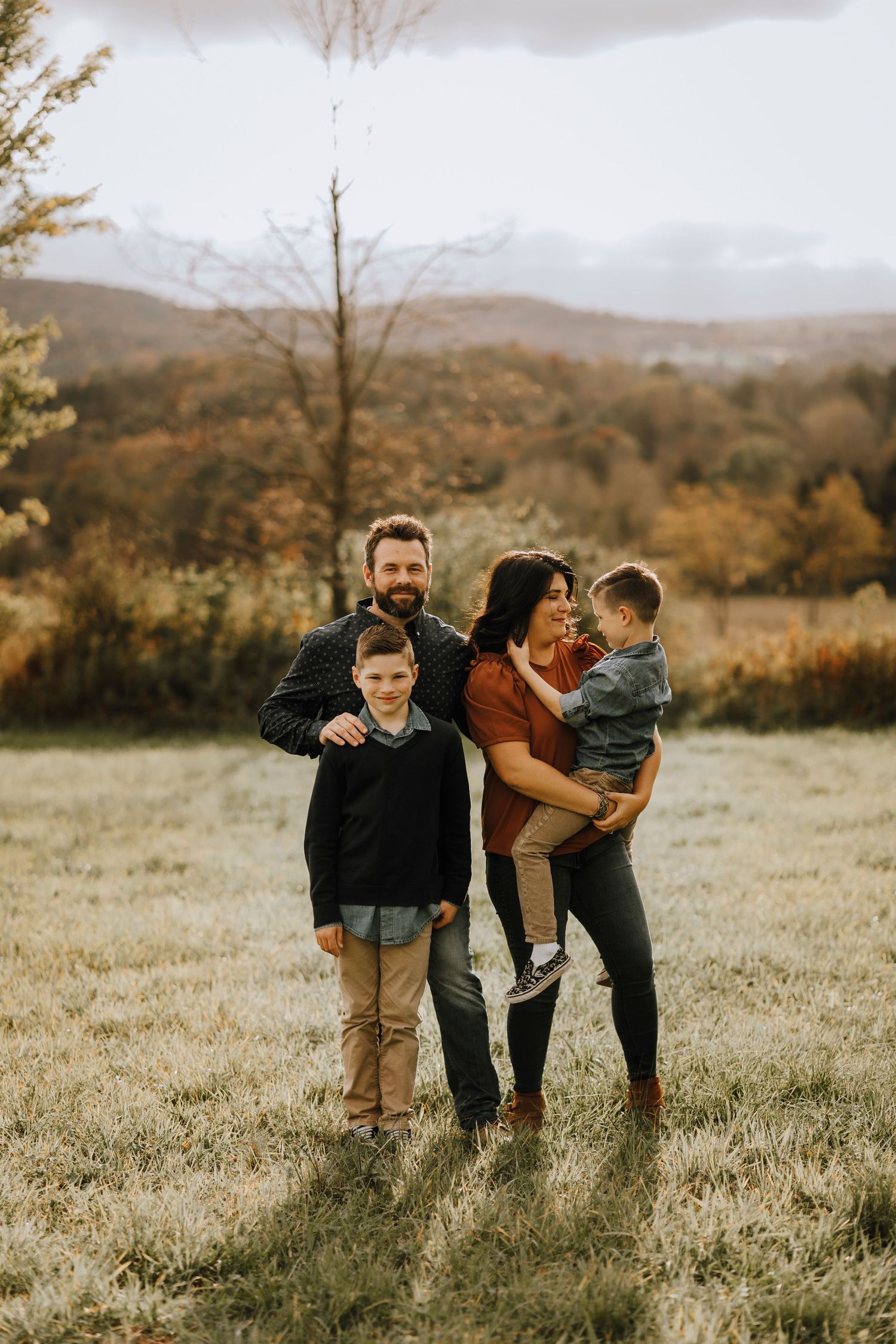Family of four enjoying an autumn day together in a mountainous field during golden hour.