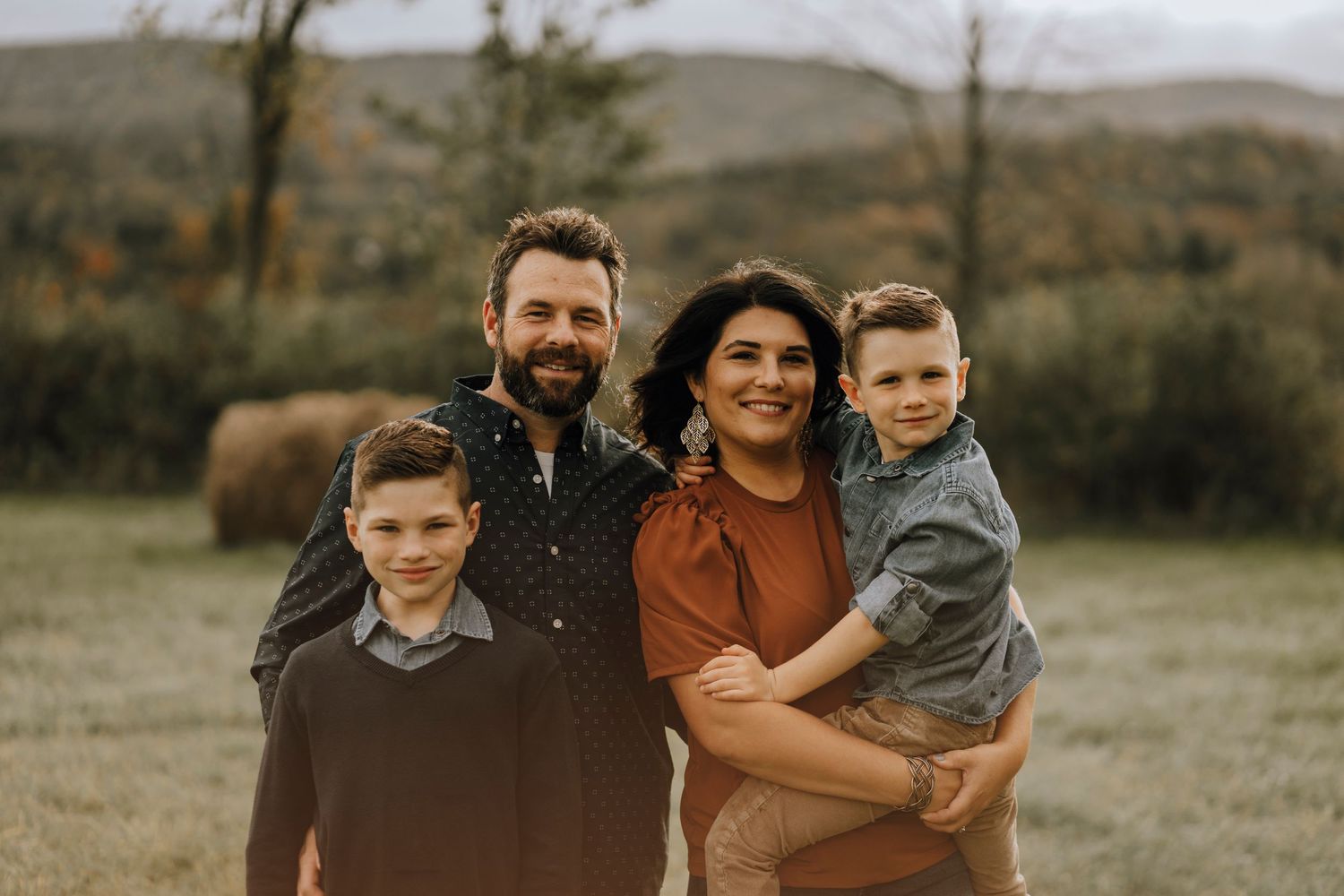 Fall family portrait with mountains and autumn foliage in the background.