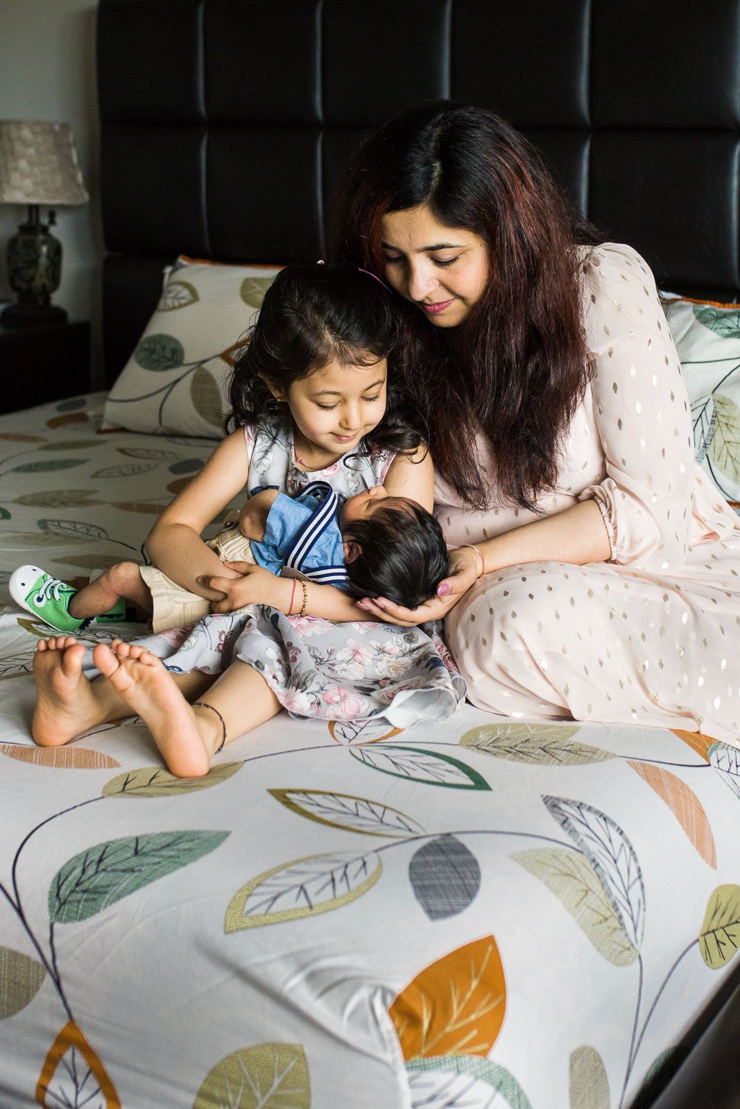 Mother and sibling holding the newborn baby together