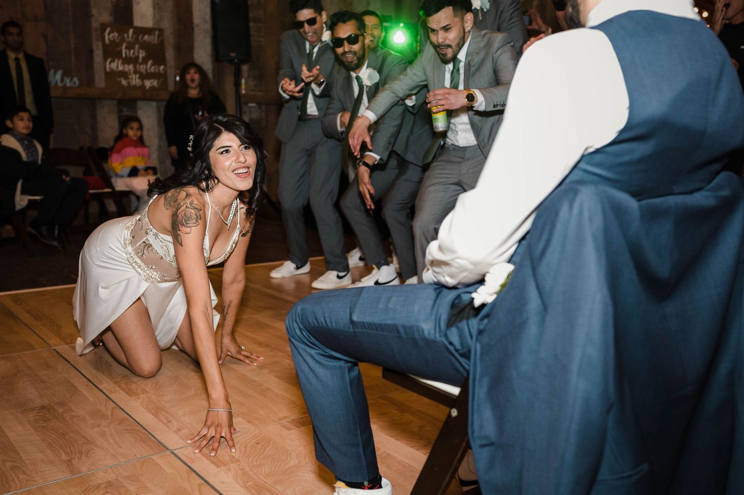 Wedding reception guests enjoying energetic dancing on a rustic wooden floor.