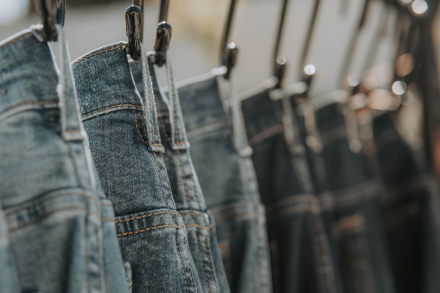 Close-up rack of blue denim jeans hanging in retail store display.