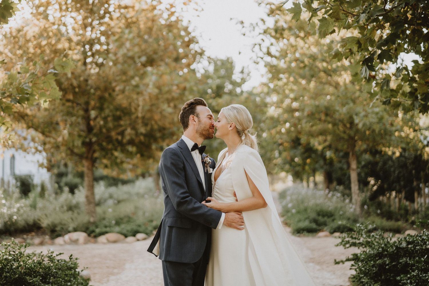 An intimate wedding moment photographed in a lush garden setting with autumn colors.