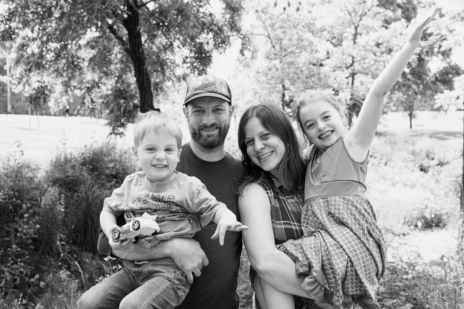 Natural light family portraits captured in a rustic outdoor setting.