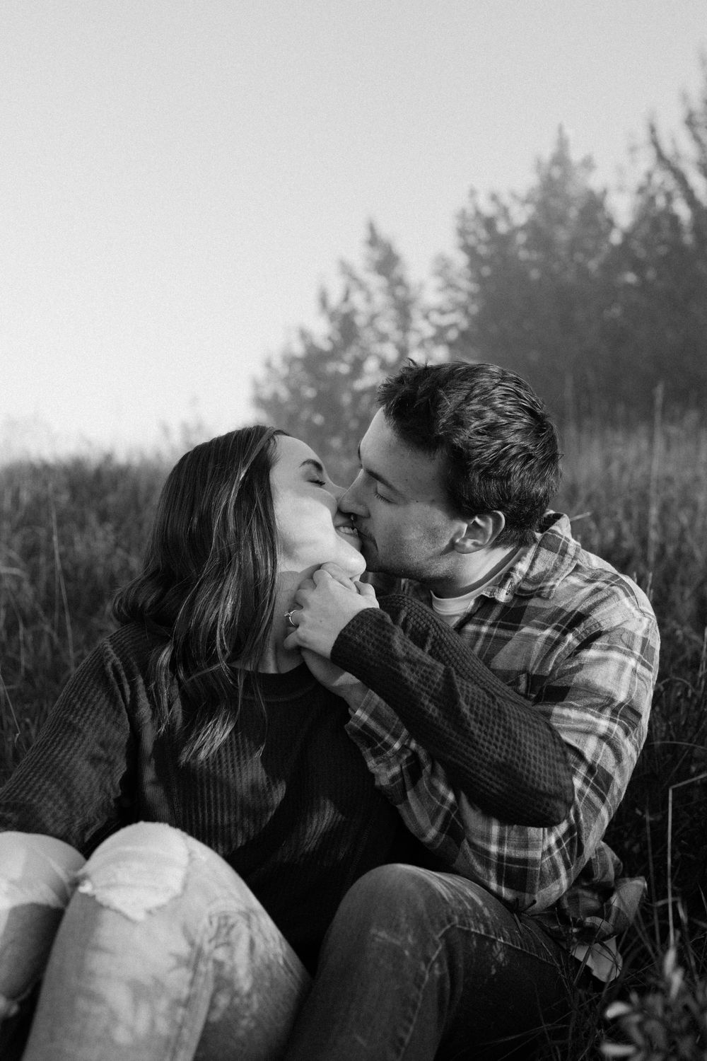 Black and white intimate portrait of a couple among trees.